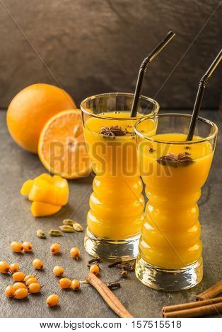 orange sea buckthorn juice with orange, sea buckthorn , cinnamon, carnation and cardamon  on a dark table