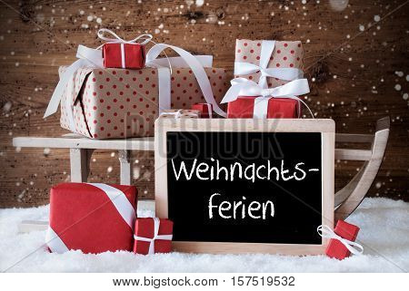 Chalkboard With German Text Frohe Weihnachten Means Merry Christmas. Sled With Christmas And Winter Decoration And Snowflakes. Gifts And Presents On Snow With Wooden Background.