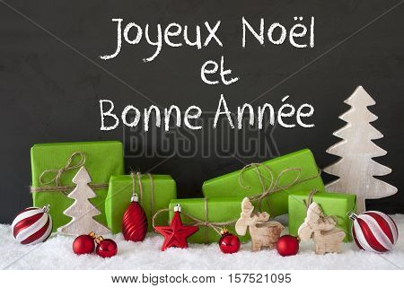 French Text Joyeux Noel Et Bonne Annee Means Merry Christmas And Happy New Year. Green Gifts With Christmas Decoration Like Tree, Moose Or Red Balls. Black Cement Wall As Background With Snow.