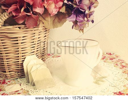 cup and tea bag on tablecloth background vintage fiters