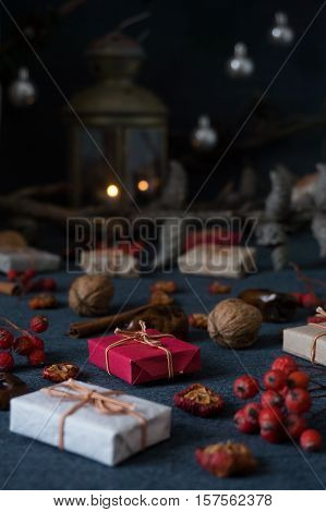 Christmas gifts, rowan, nuts, old lamp and pine branch with cones on dark surface