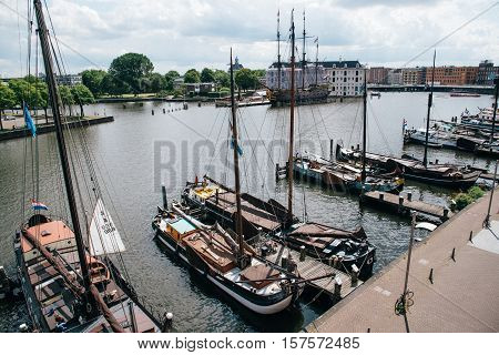 Amsterdam Netherlands - August 1 2016: Old sailing ships moored in the pier near The National Maritime Museum in Amsterdam a cloudy day. High angle view