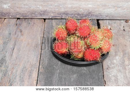 rambutan sweet fruit fresh in plate on wood background : Select focus with shallow depth of field.
