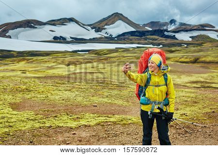 woman hiker photographer taking selfie on the rhyolite mountains background in Iceland