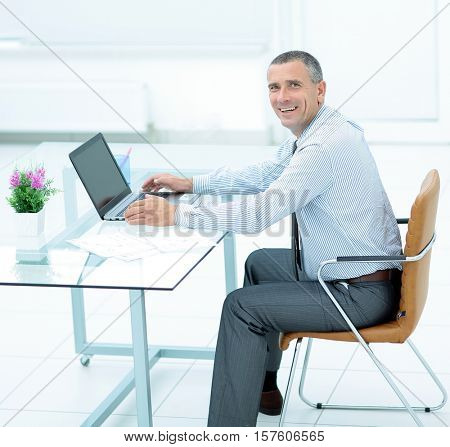 successful smiling businessman working on laptop at Desk in offi