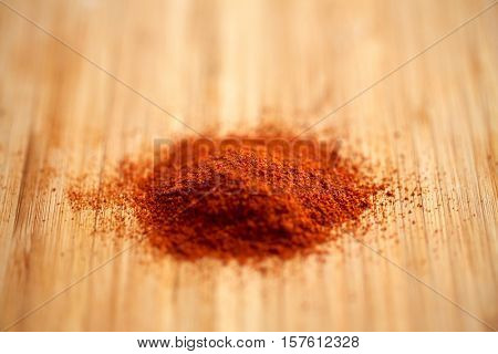 cooking, spice and ethnoscience concept - cayenne, chili pepper or paprika powder on wood