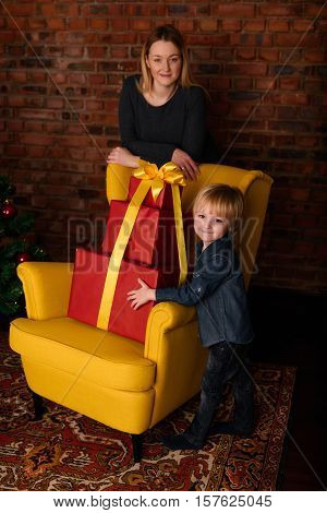 Mom gives a child a Christmas gift near the Christmas tree