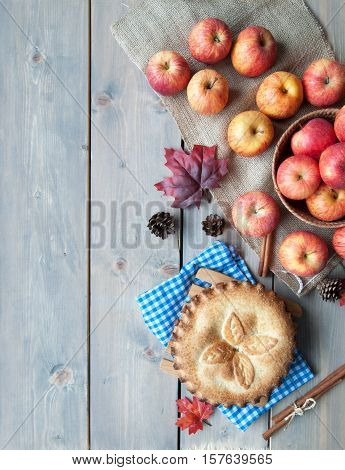Apple pie with fruit ingredients and cinammon sticks on a wooden table