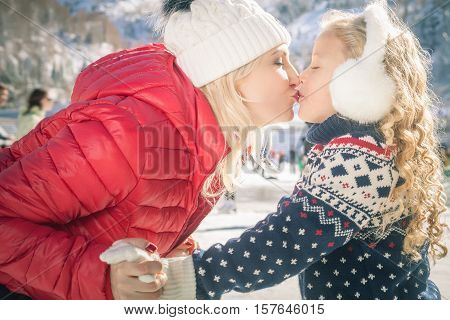 Happy mother and daughter kissing outdoor, ice skating at ice rink. Mother and daughter has winter activities. Mom, kids. Medeo stadium. Almaty.