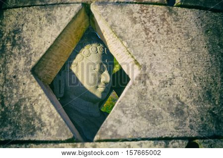 Carved stone buddha statue inside small stupa. Vintage filter