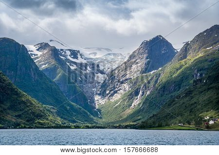 The Briksdal glacier and rocks view from the fjord water. Popular touristic attraction, Briksdalsbreen, Norway.