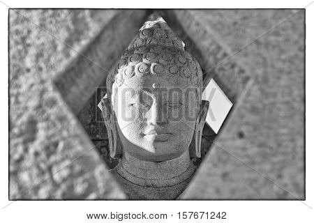 Carved stone buddha statue inside small stupa. Black and white photograph with a vintage border