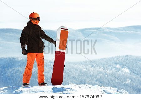 Snowboarder posing with snowboard against mountains.Sheregesh ski resort