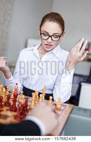 Young businesswoman playing chess with businessman analyzing situation