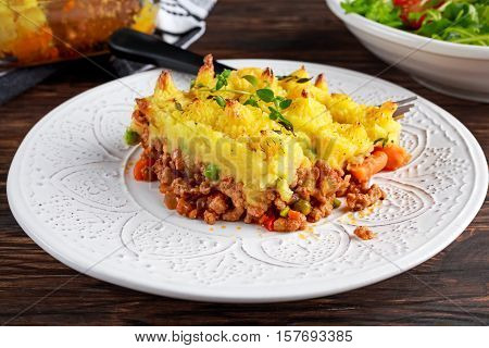Traditional british shepard pie on plate with salad.