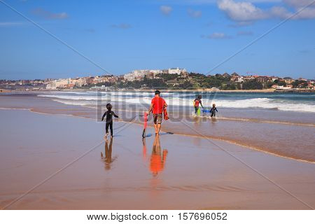 SANTANDER SPAIN - AUGUST 20: Father and son carrying their surfboard on the beach on August 20 2016