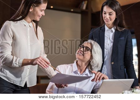 Giving a counsel. Two young female colleagues discussing their work results with boss while sharing ideas and working hard.