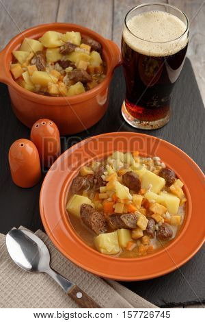 Traditional Irish dish Dublin coddle with sausages and beer on a table