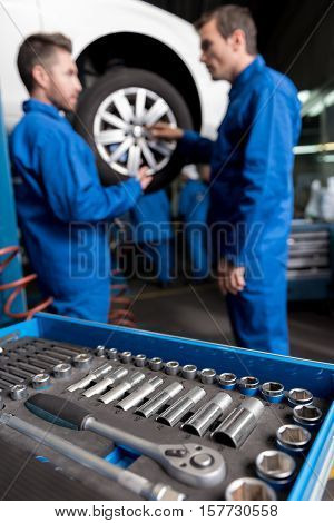Well equiped. Selective focus of car tools with professional car mechanics standing in the background and going to change a wheel