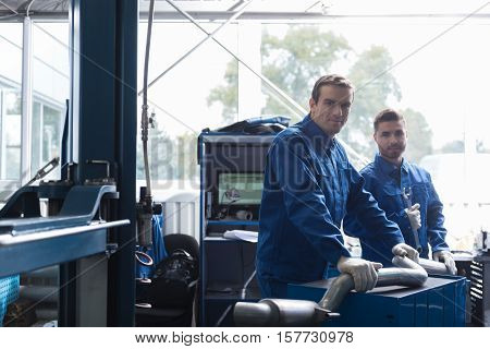 Work with pleasure. Professional car mechanics reparing muffler and working together in auto service