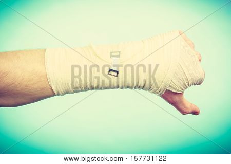 Bad news and information. Medicine aspects. Male hand with bandage showing thumb down sign symbol.