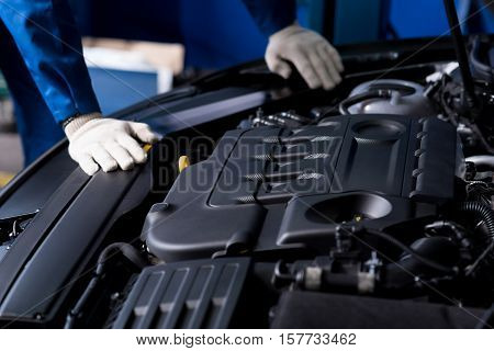 Important work. Close up of engine of powerful car while professioanl mechanic checking it out