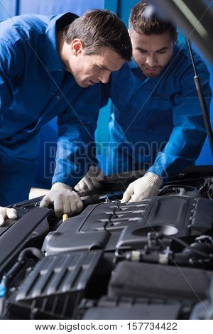 We should deal with itConcentrated experienced, mechanics talkign and discussing break out while repairing car engine
