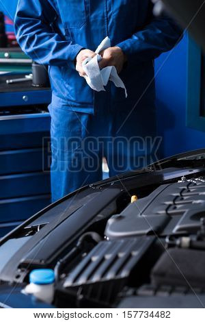 Ready for usage. Close up of car engine while professional mechanic standing in the background and wiping his hands