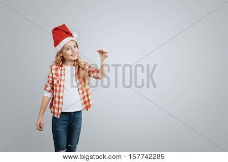 Share positivity. Cheeful smiling little girl holding Christmas bell and smiling while celebrating New Year