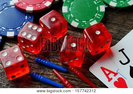 A close up image of poker chips, red dice, and cribbage pegs.