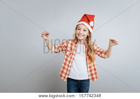 Let it snow. Cheerful delighted little girl smiling and ringing bells while standing islated on rey background