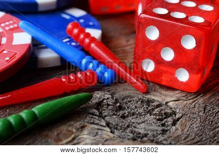 A close up image of poker chips, red dice, and cribbage pegs.
