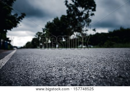 View from below of asphalt road over blurred trees and cloudscape background. Paved road through the forest. Outdoors.