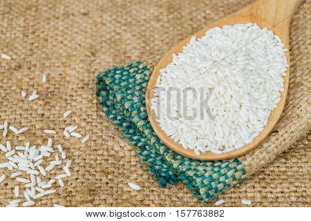 Glutinous rice in wooden spoon with hemp sacks background