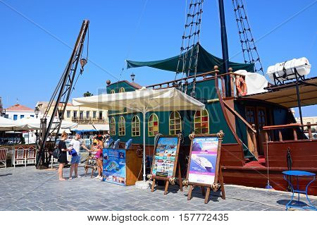 RETHYMNO, CRETE - SEPTEMBER 15, 2016 - Tourists looking at signs by a Galleon ship in the inner harbour with waterfront restaurants to the rear Rethymno Crete Greece Europe, September 15, 2016.
