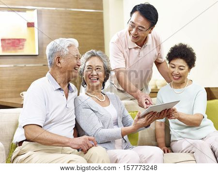 two active senior asian couples looking at tablet computer happy and laughing