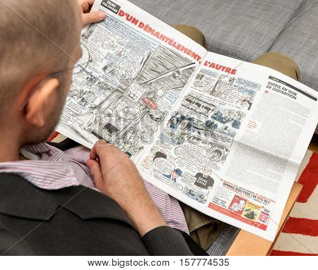 PARIS FRANCE - NOV 12 2016: Man reading Charlie Hebdo magazine on after Donal Trump elections as USA President - having fun reading cartoon satire about Paris