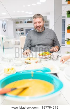 Family gathering eating meal around kitchen table