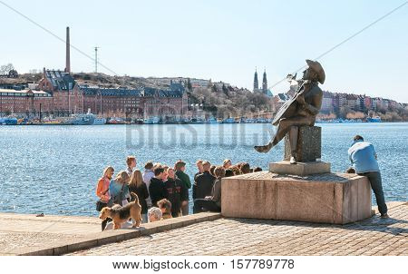 STOCKHOLM, SWEDEN - APRIL 14, 2010: Group of people near Evert Taube Monument. On the background is Riddarfjarden Bay and Hogalid Church. Evert Taube was a Swedish author, artist, composer and singer