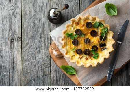 Homemade quiche tart with chicken eggplant olives and cheese on old wooden background.Top view. Place for text. Selective focus.