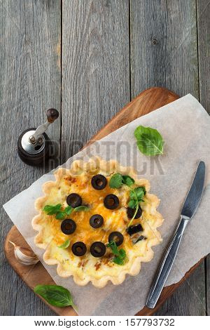 Homemade quiche tart with chicken eggplant olives and cheese on old wooden background.Top view. Place for text. Selective focus.