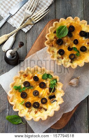 Homemade quiche tart with chicken eggplant olives and cheese on old wooden background.Top view. Place for text. Selective focus.