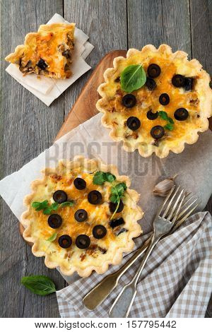 Homemade quiche tart with chicken eggplant olives and cheese on old wooden background.Top view. Place for text. Selective focus.