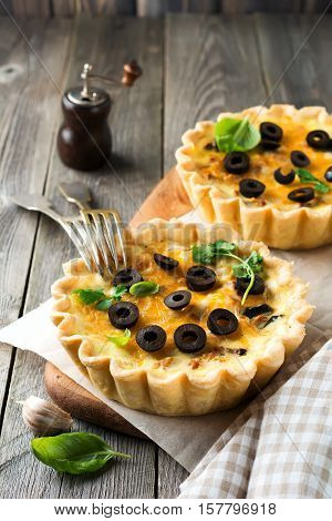 Homemade quiche tart with chicken eggplant olives and cheese on old wooden background. Selective focus.