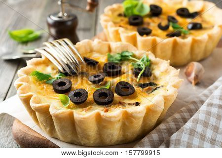 Homemade quiche tart with chicken eggplant olives and cheese on old wooden background. Selective focus.