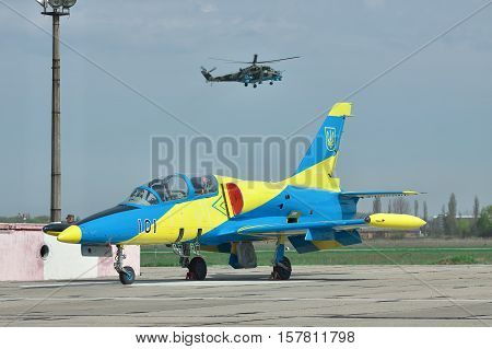 Vasilkov Ukraine - April 24 2012: Ukraine Air Force Aero L-39 Albatros parked on the apron of the airfield and Mil-Mi-24 attack helicopter landing on the runway on the background