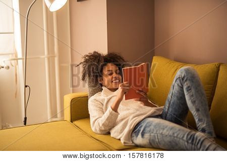 Beautful african american woman reading a book at home.