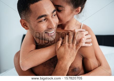 Tender young couple hugging and kissing on bed at home