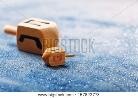 Wooden dreidels for Hanukkah on light sparkling background