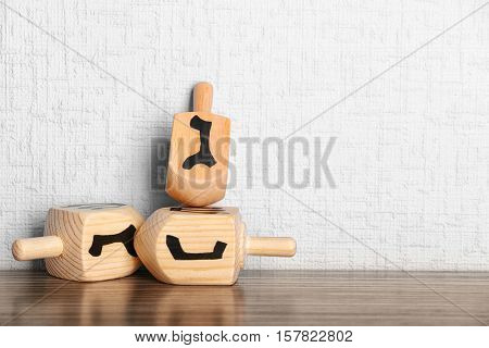 Dreidels for Hanukkah on wooden table against light textured wall